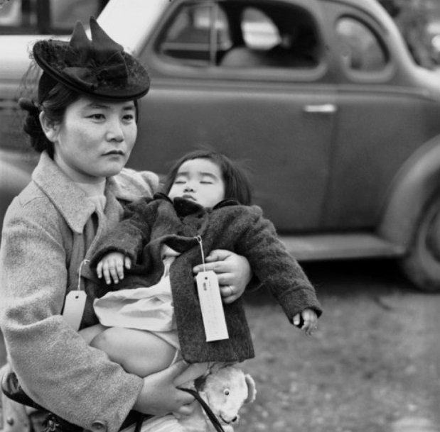 female wearing a hat and jacket while holding a child