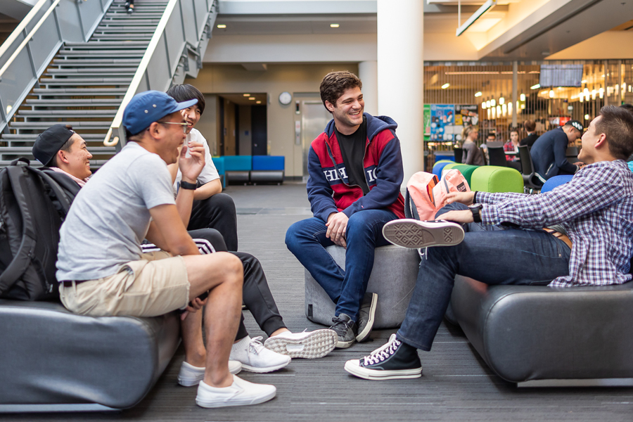 Five smiling students sit on couches in The Grove.