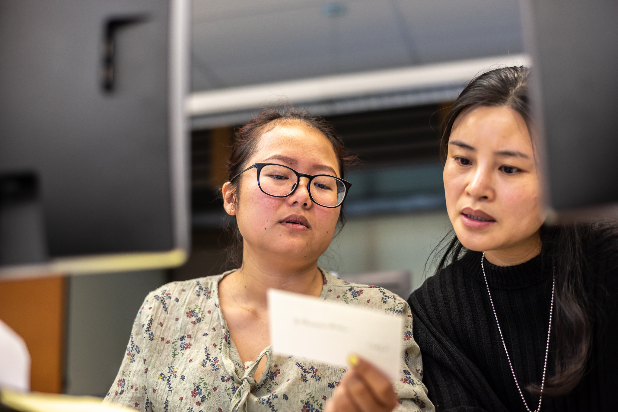 two females looking at a white notecard