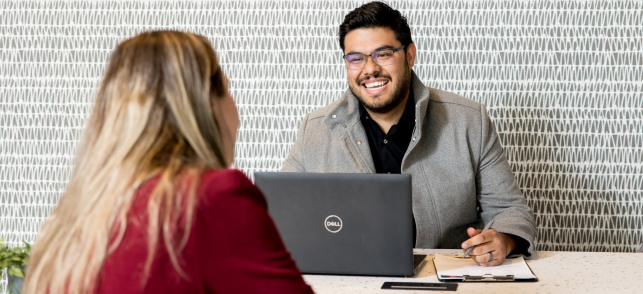 male with glasses on a laptop talking to a female