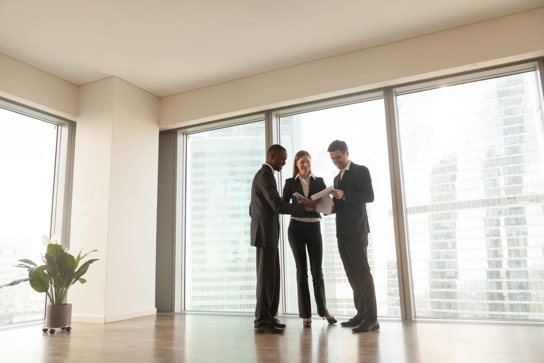 people standing in a room wearing suites looking at papers