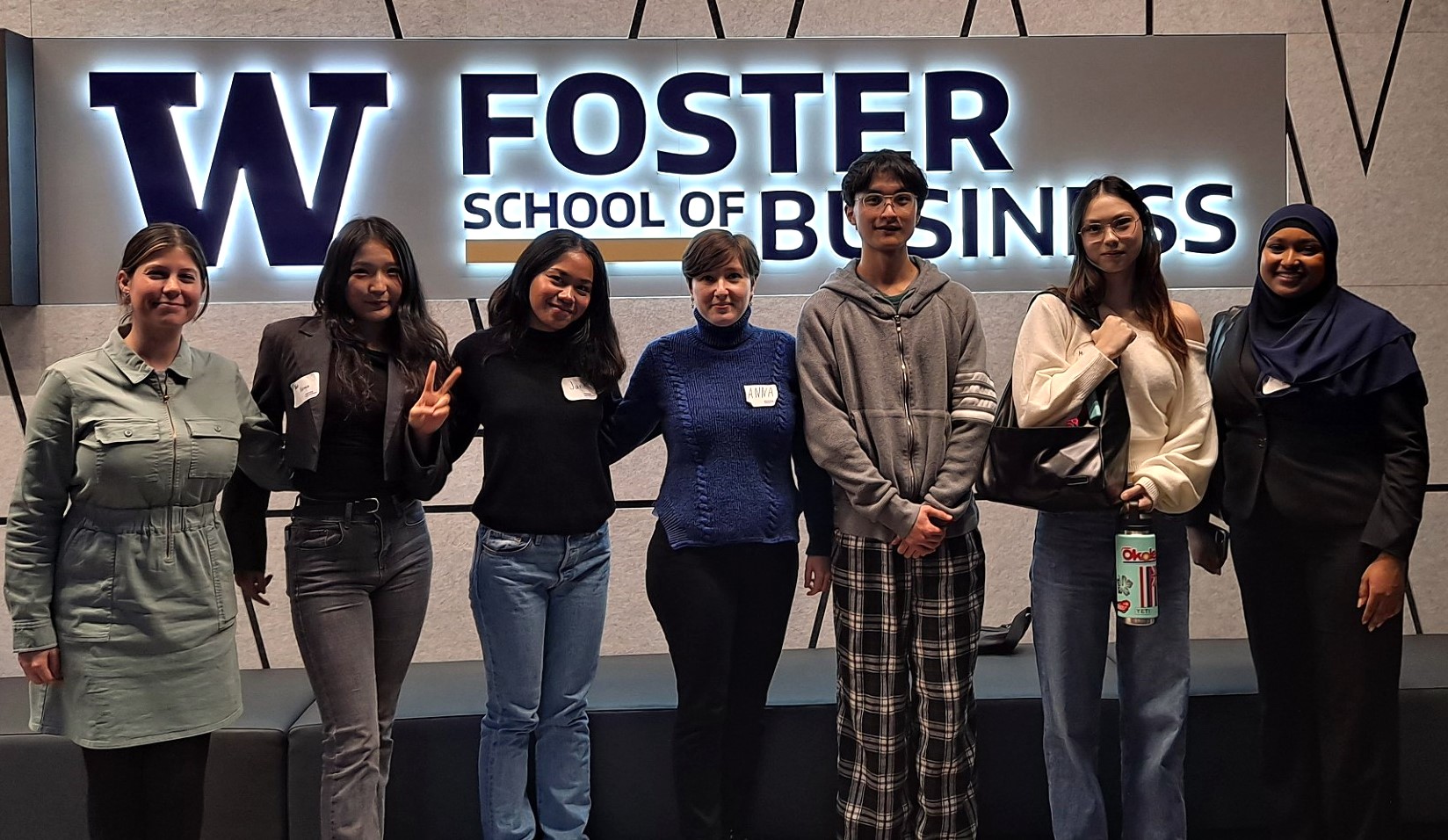 students standing together in front of a sign that reads W Foster School of business 