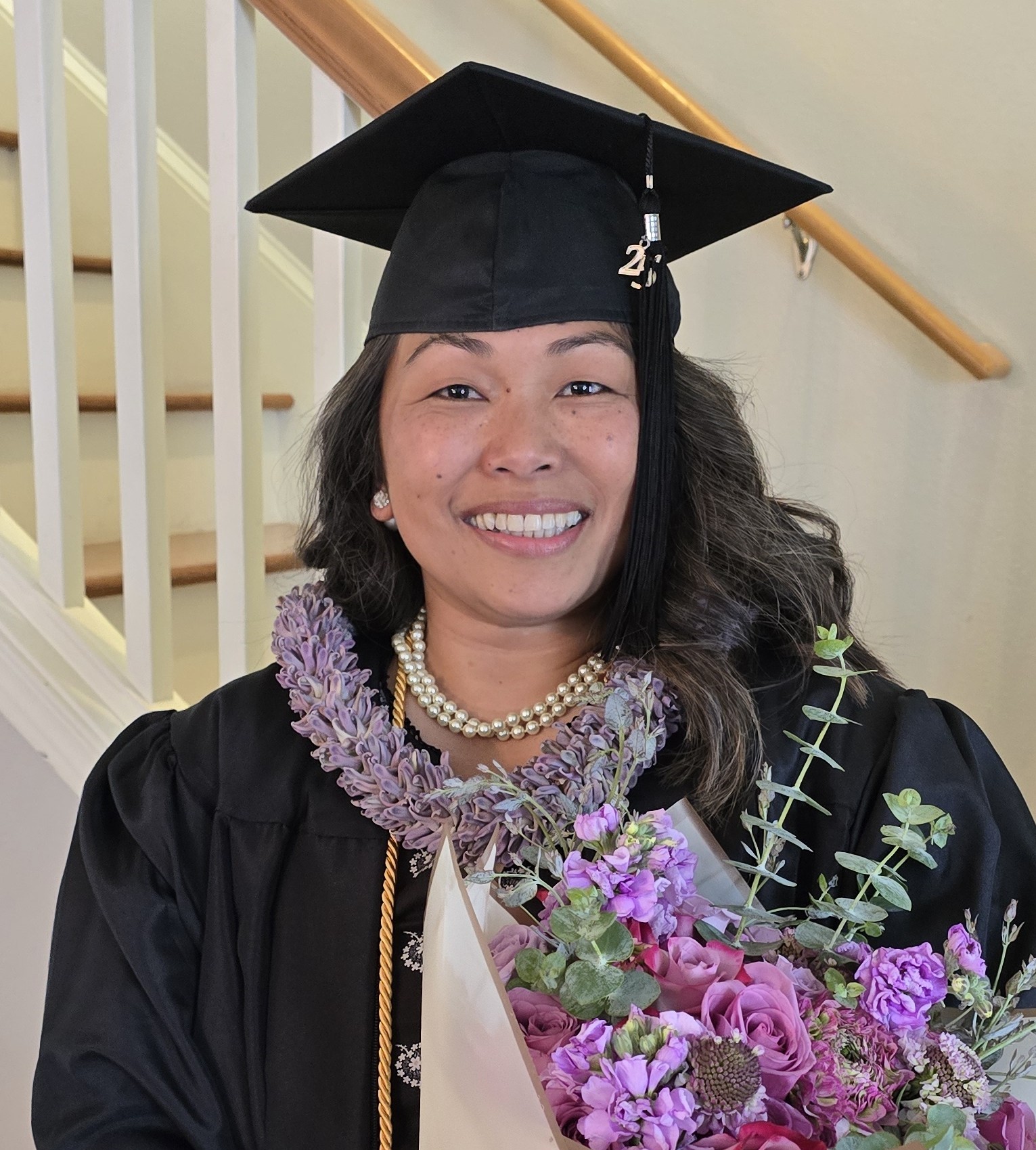 north Seattle college female graduate Jovie Santos wearing a black cap and gown holding flowers 