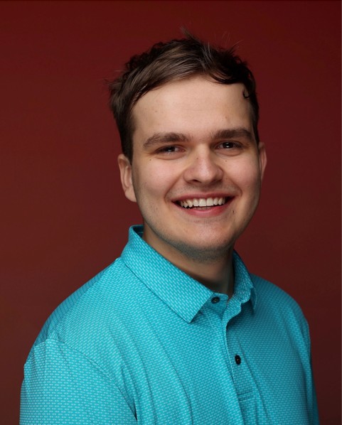 male wearing a blue shirt with a red background