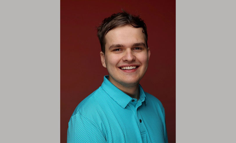 male wearing a blue shirt with a red background 