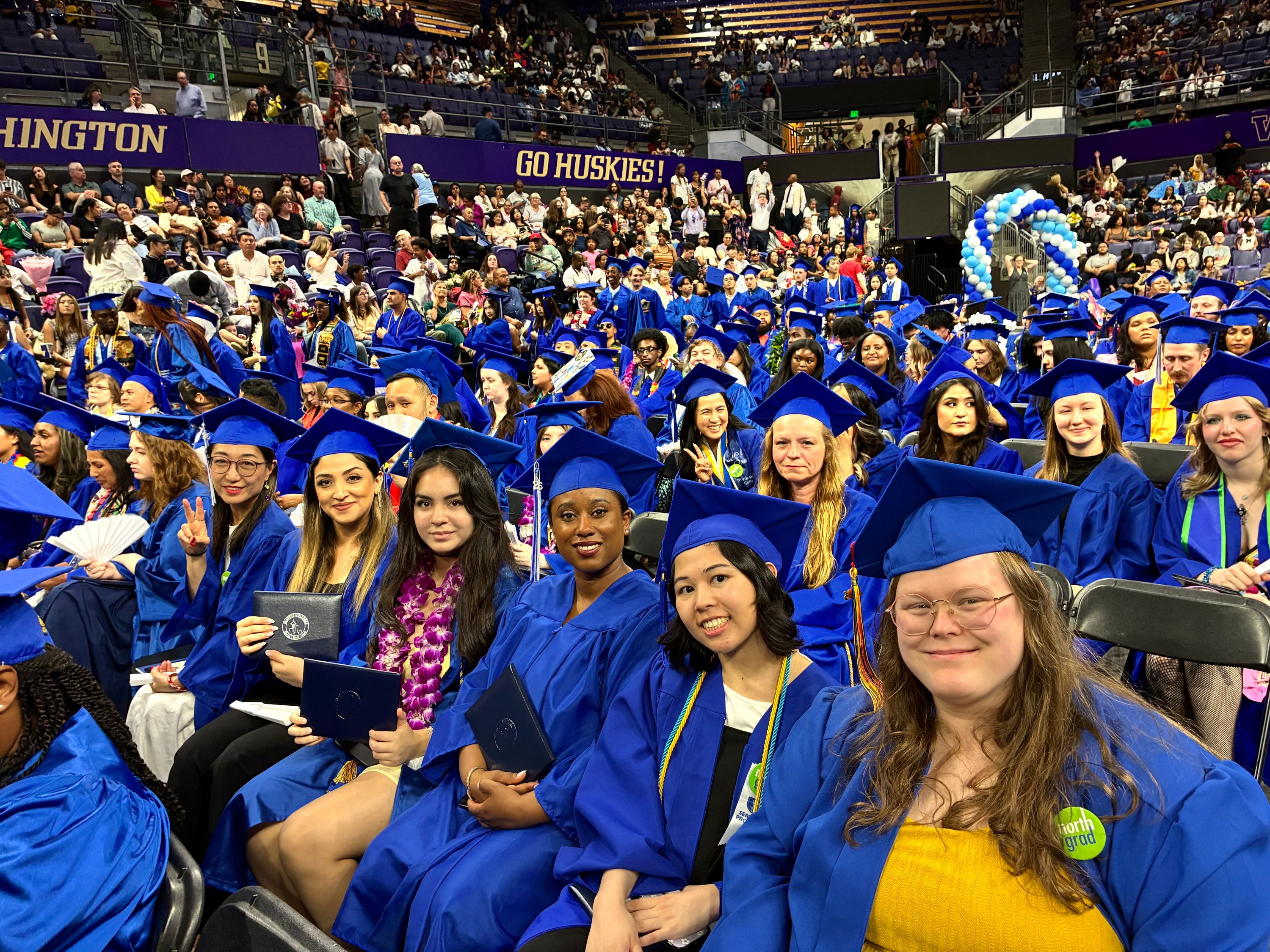 graduates wearing blue caps and gowns sitting together 