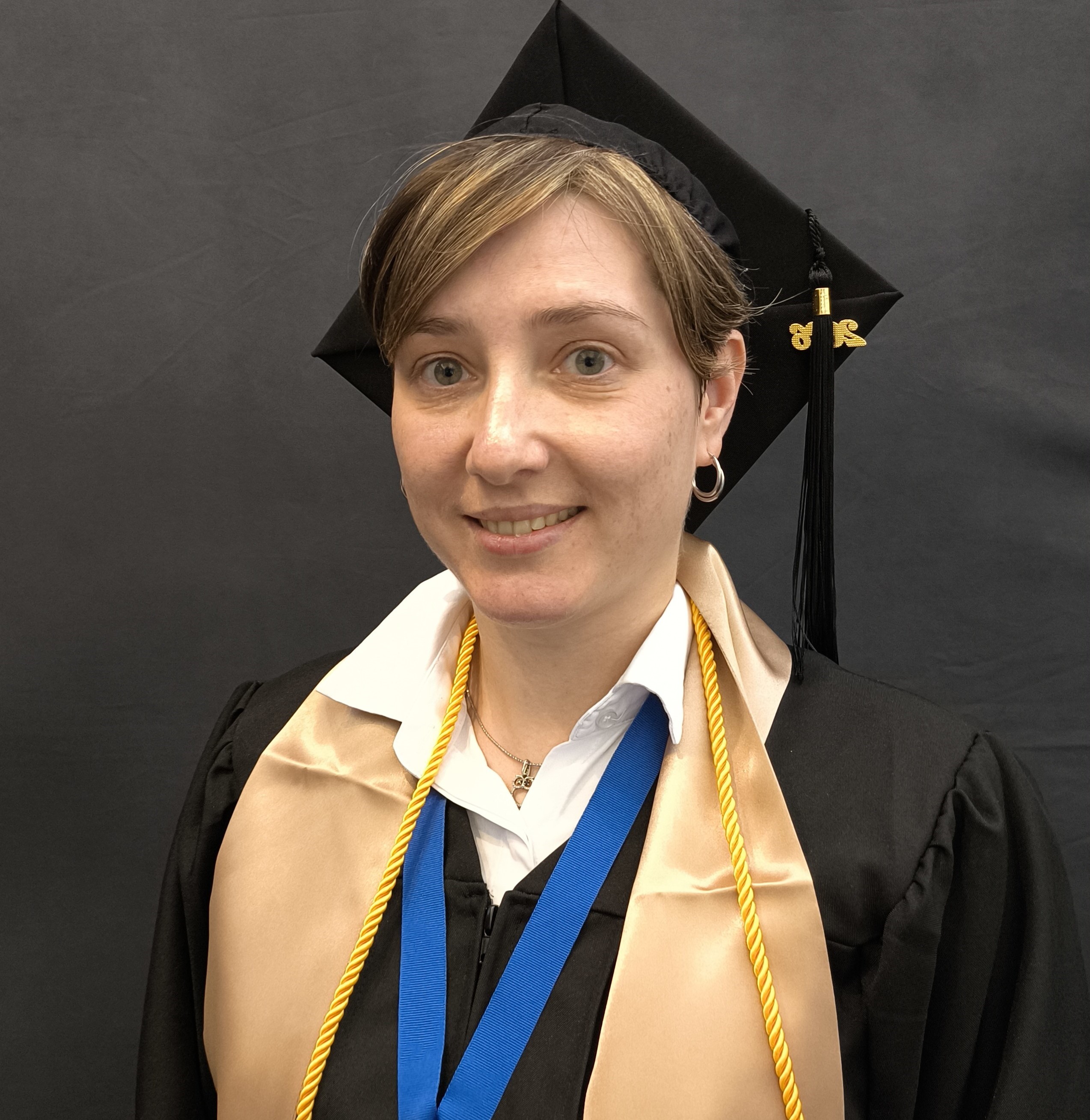 female graduate wearing a black cap and gown with a blue ribbon medal 