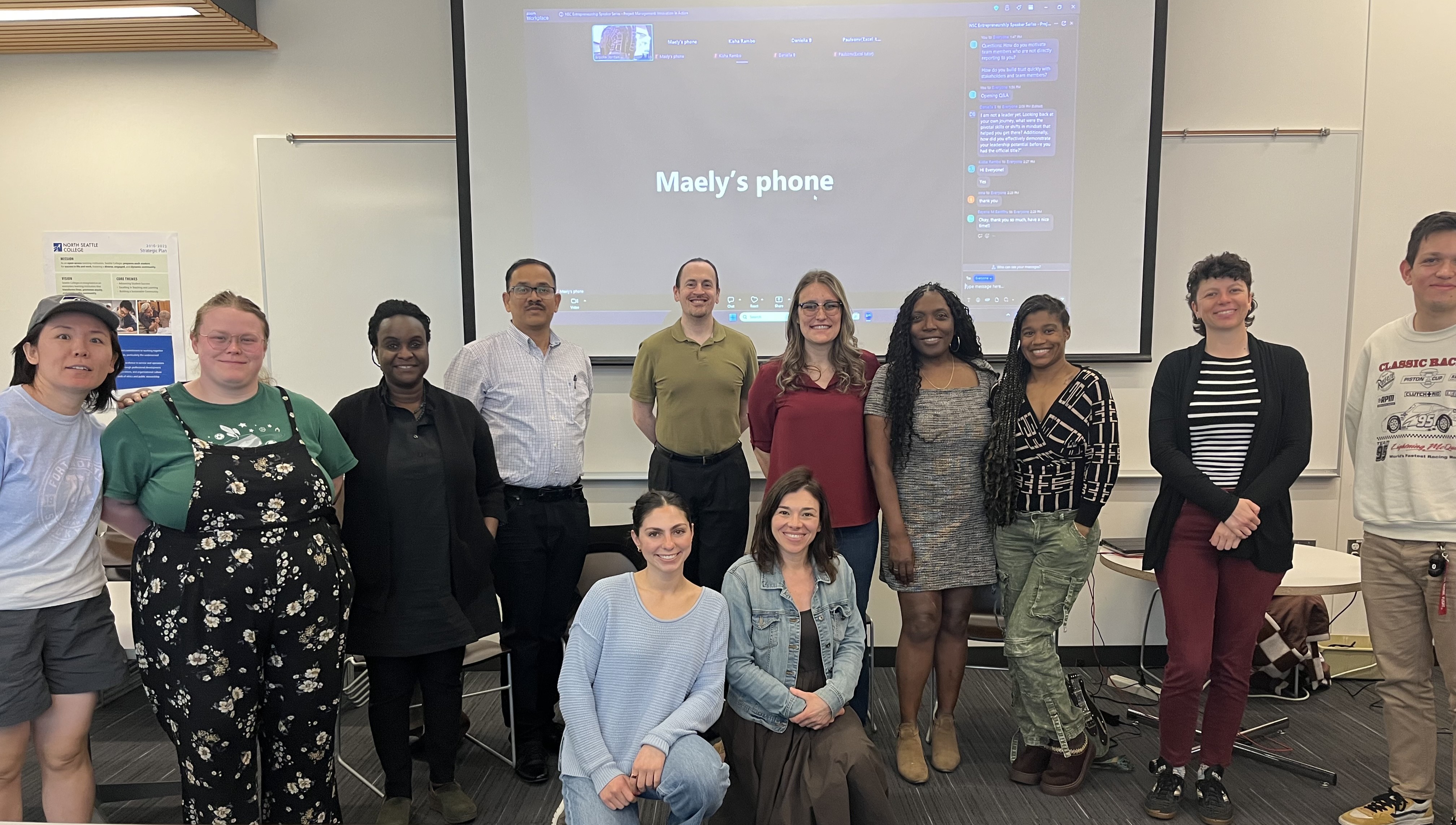 men and women standing in front of a projector screen in a classroom 