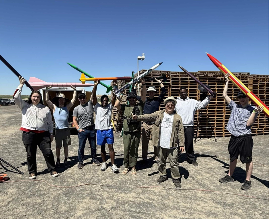 a group of people standing outside in a desert holding up rockets 
